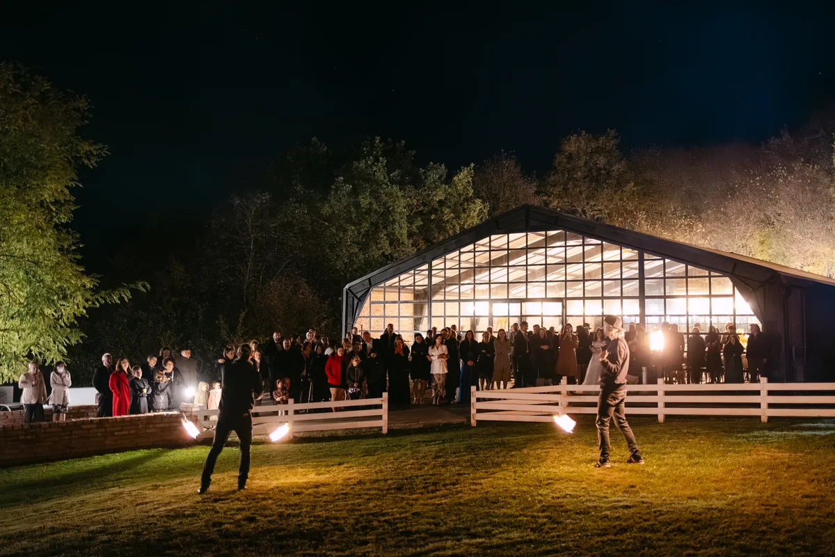 clădirea La Foret noaptea, luminată din interior, cu invitații pe peluză la show-ul cu foc