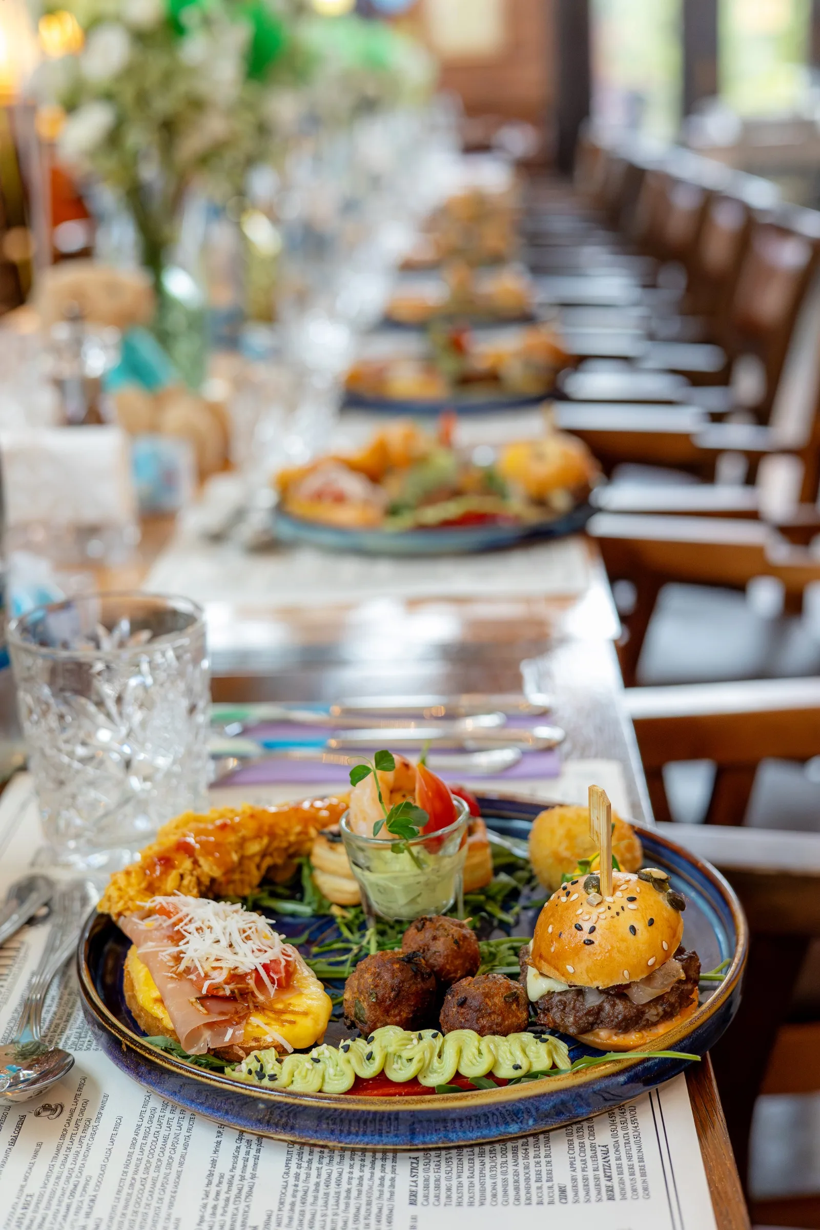 Platou de aperitive servit la un botez într-un restaurant din Cluj-Napoca — mini-burgeri, chiftele și bruschete pe farfurie albastră