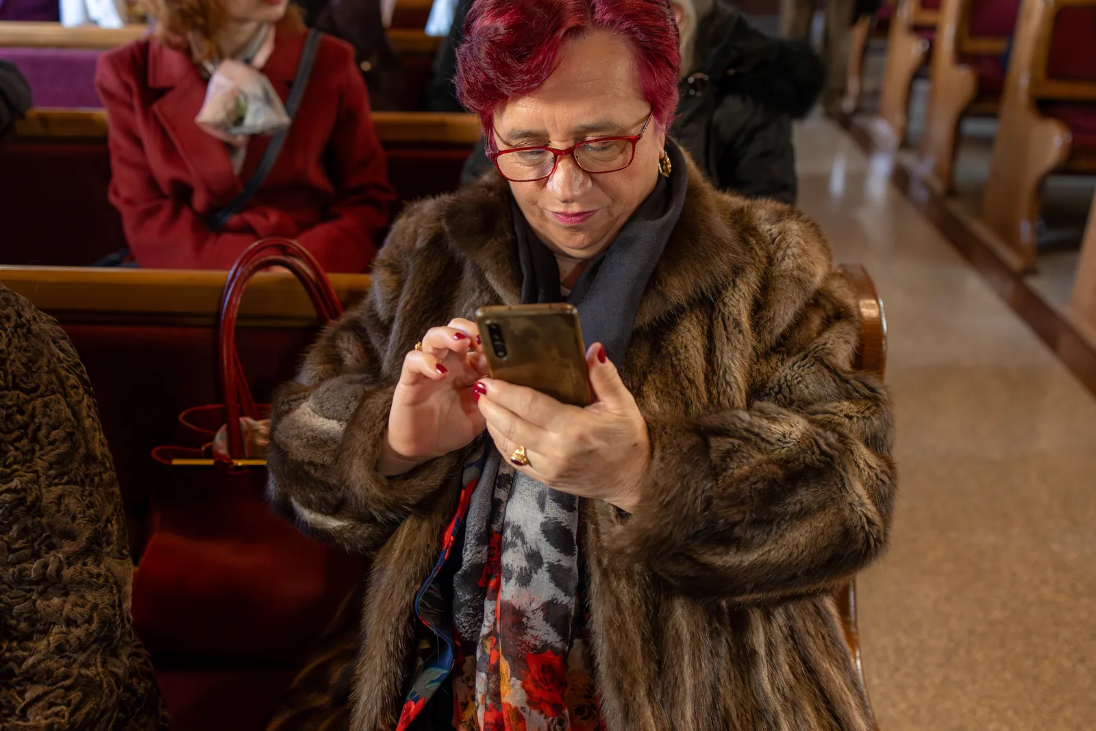 O bunică filmând cu telefonul din strană, în timpul slujbei