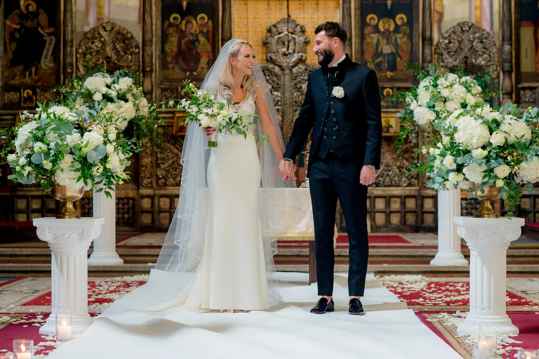 Miri în biserică, între aranjamente florale albe — portret de cuplu la o nuntă în Cluj