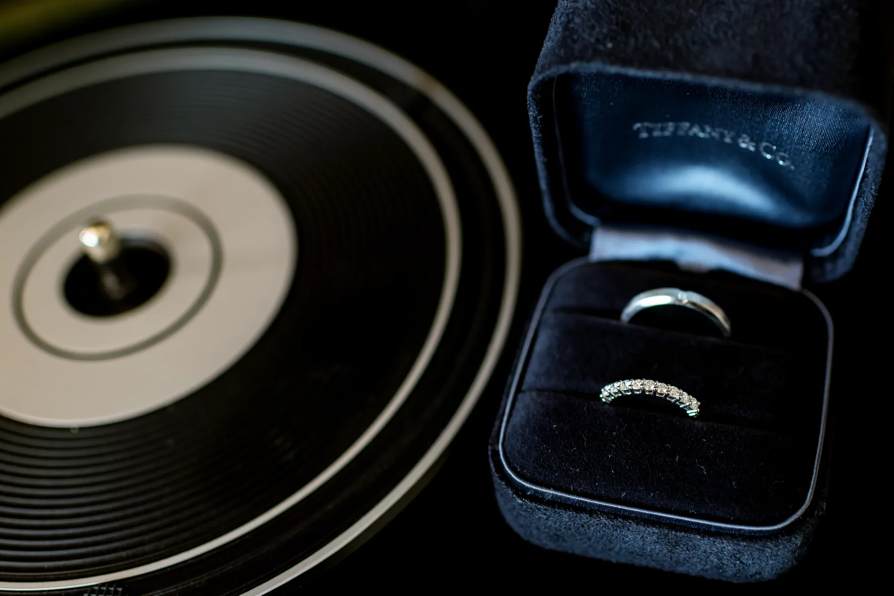 Verighete și inel de logodnă în cutie Tiffany & Co., așezate pe un vinil — detaliu de nuntă