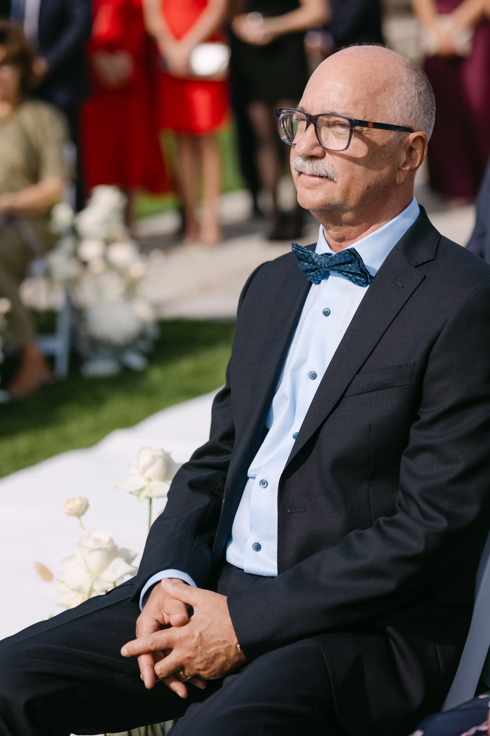 Tatăl mirelui, cu mâinile împletite, privind spre culoarul de ceremonie