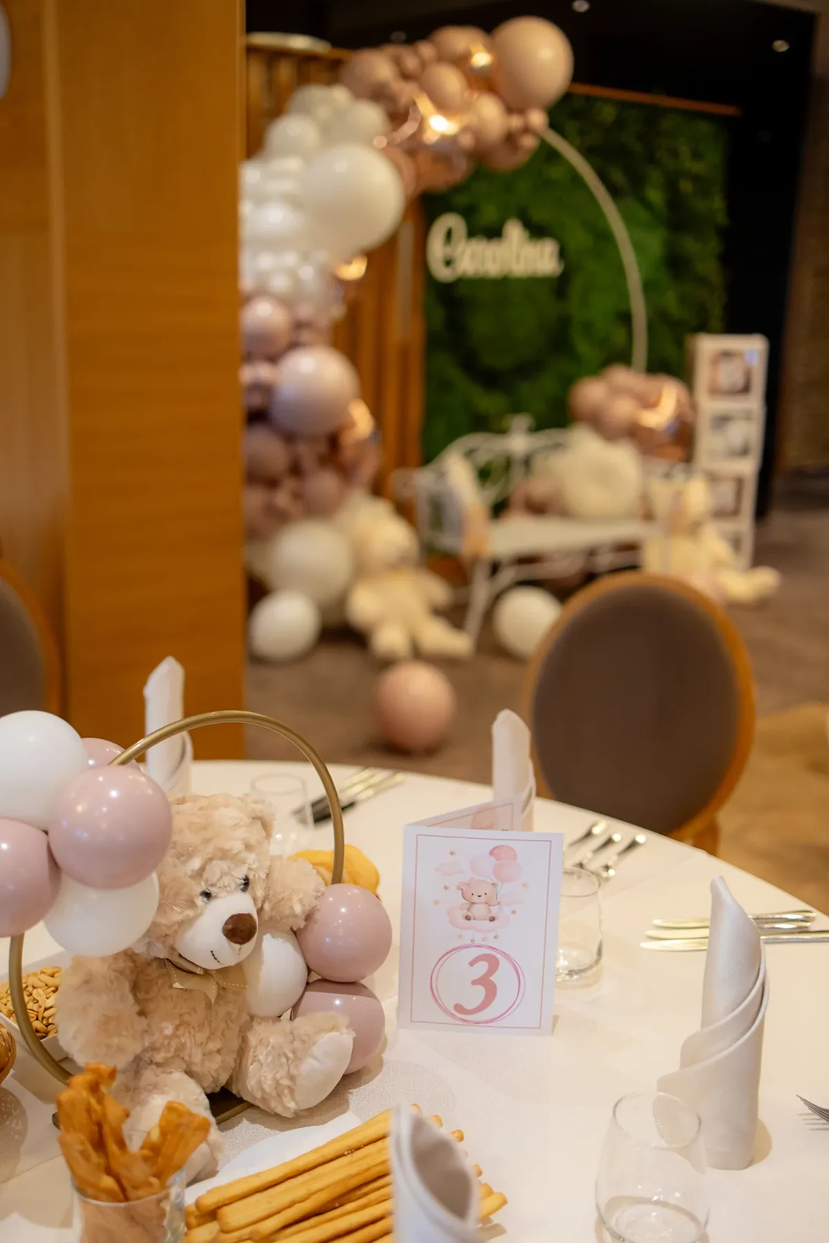 Decor de botez în tonuri pudrate la un hotel din Cluj-Napoca — arc de baloane, ursuleț pe centrul de masă și photocorner cu perete verde