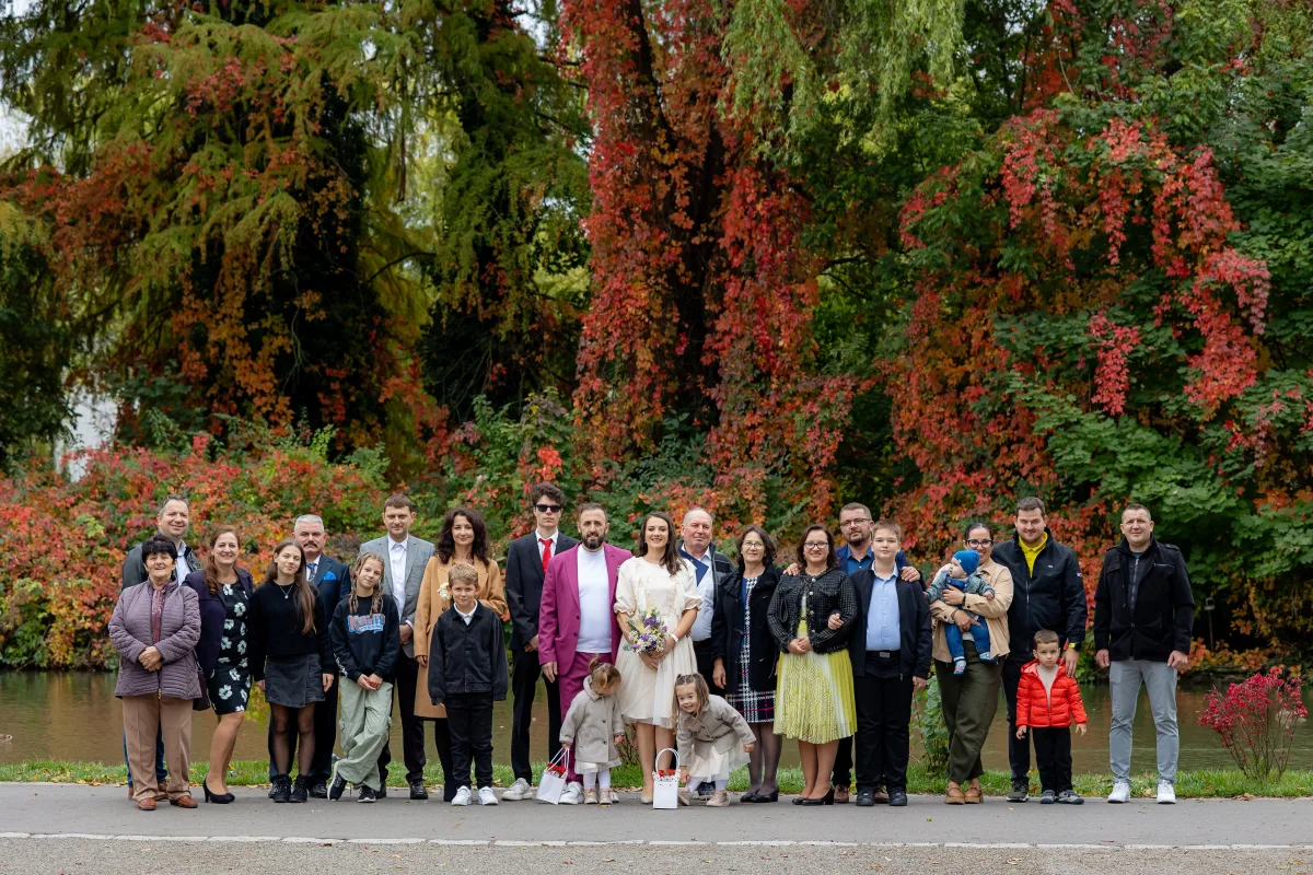 Fotografie de grup cu invitații după cununia civilă, lângă lacul din Parcul Central Cluj-Napoca, în culori de toamnă