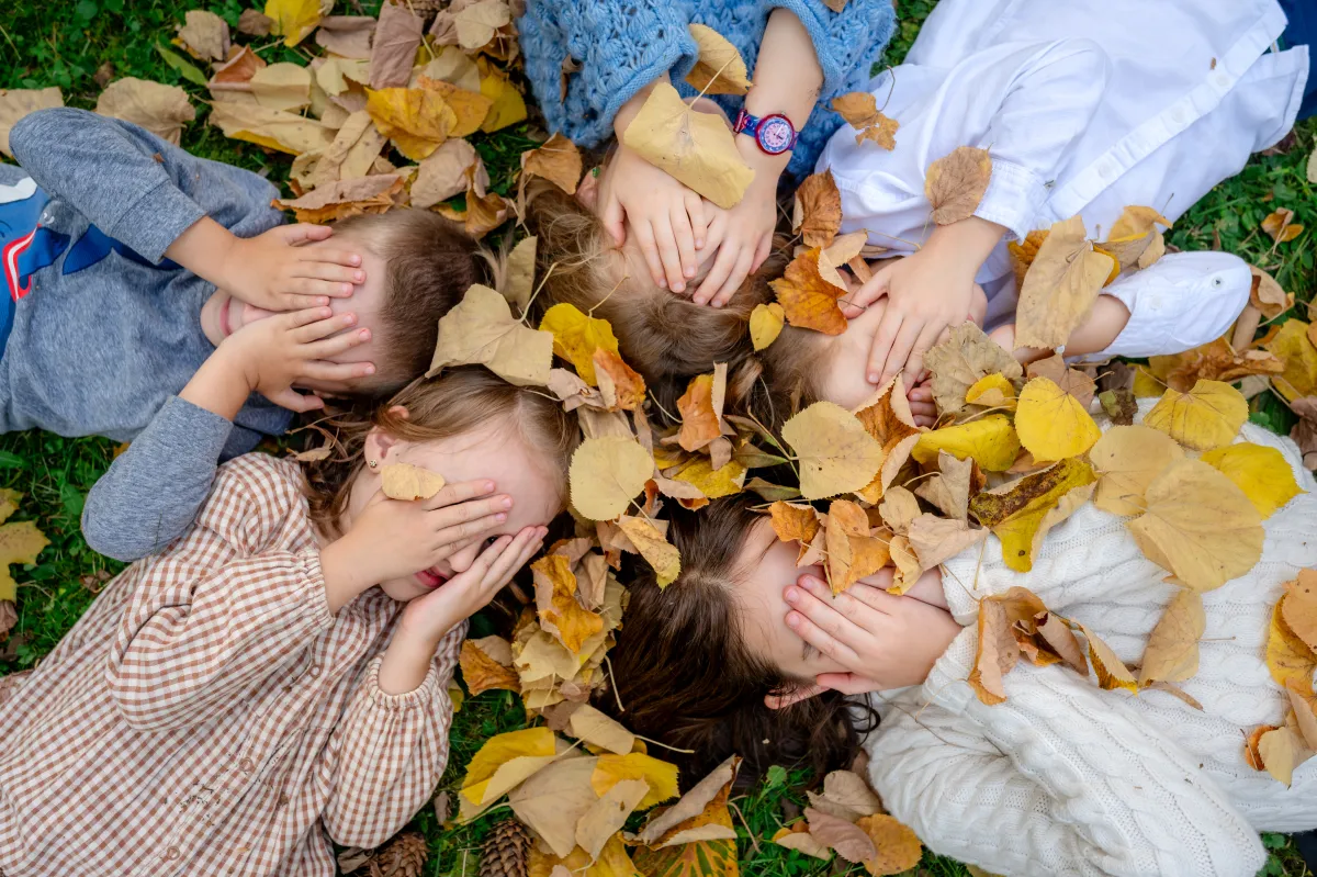 Children playing in autumn leaves, hands over their eyes — family photo session near Cluj-Napoca