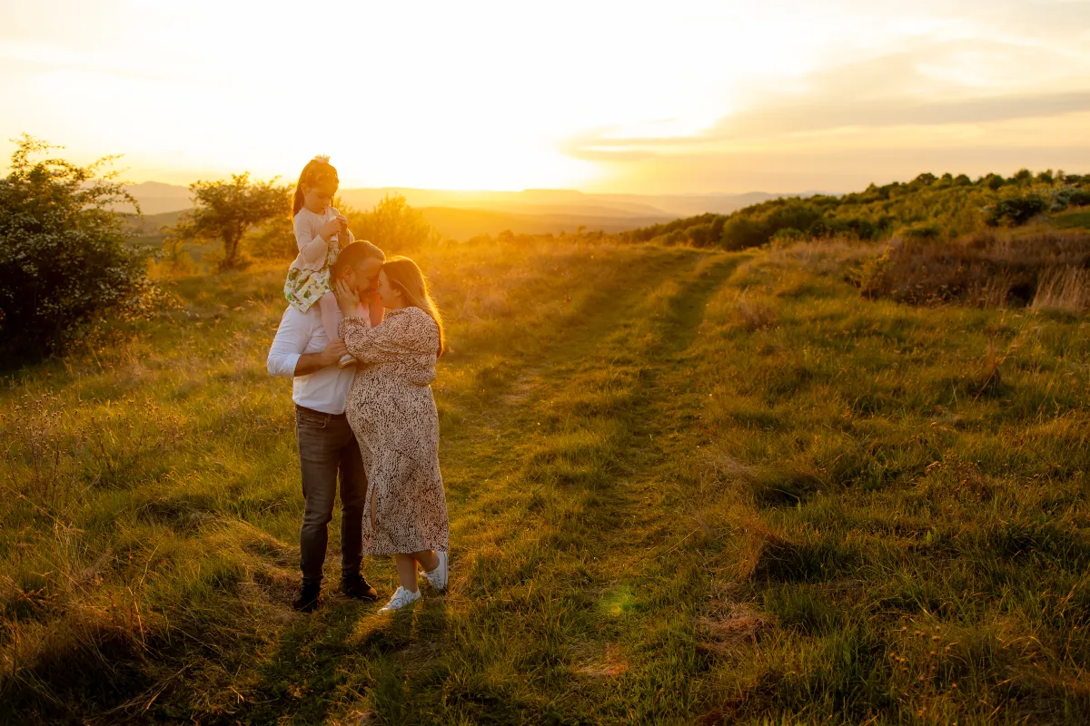 Family embracing on a hill at sunset, child on shoulders — family photo session near Cluj-Napoca