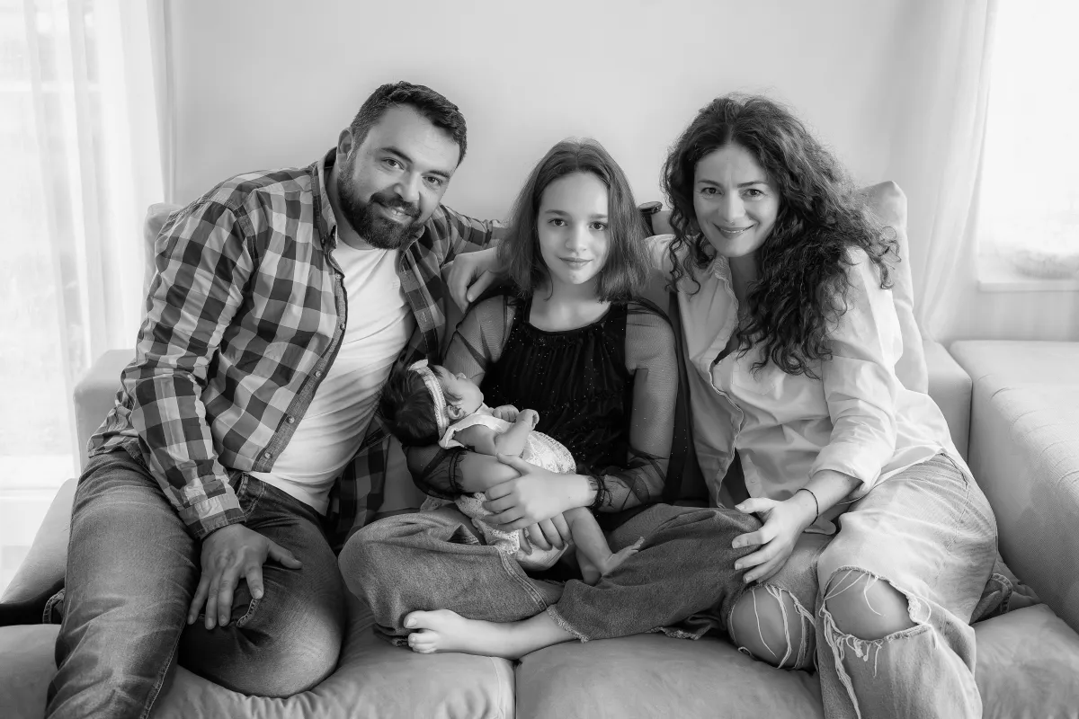 Family with a newborn on the sofa at home — family photo session documented at home in Cluj-Napoca