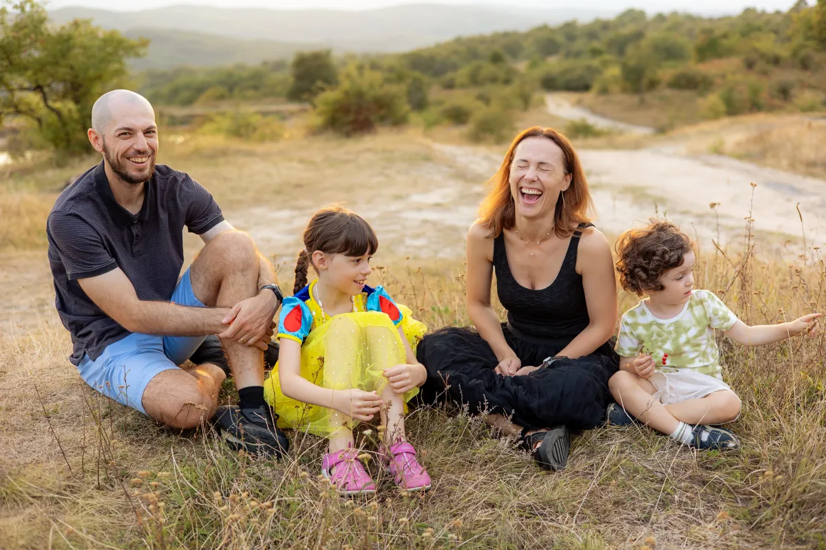 Family laughing together in the grass at a summer family photo session near Cluj-Napoca