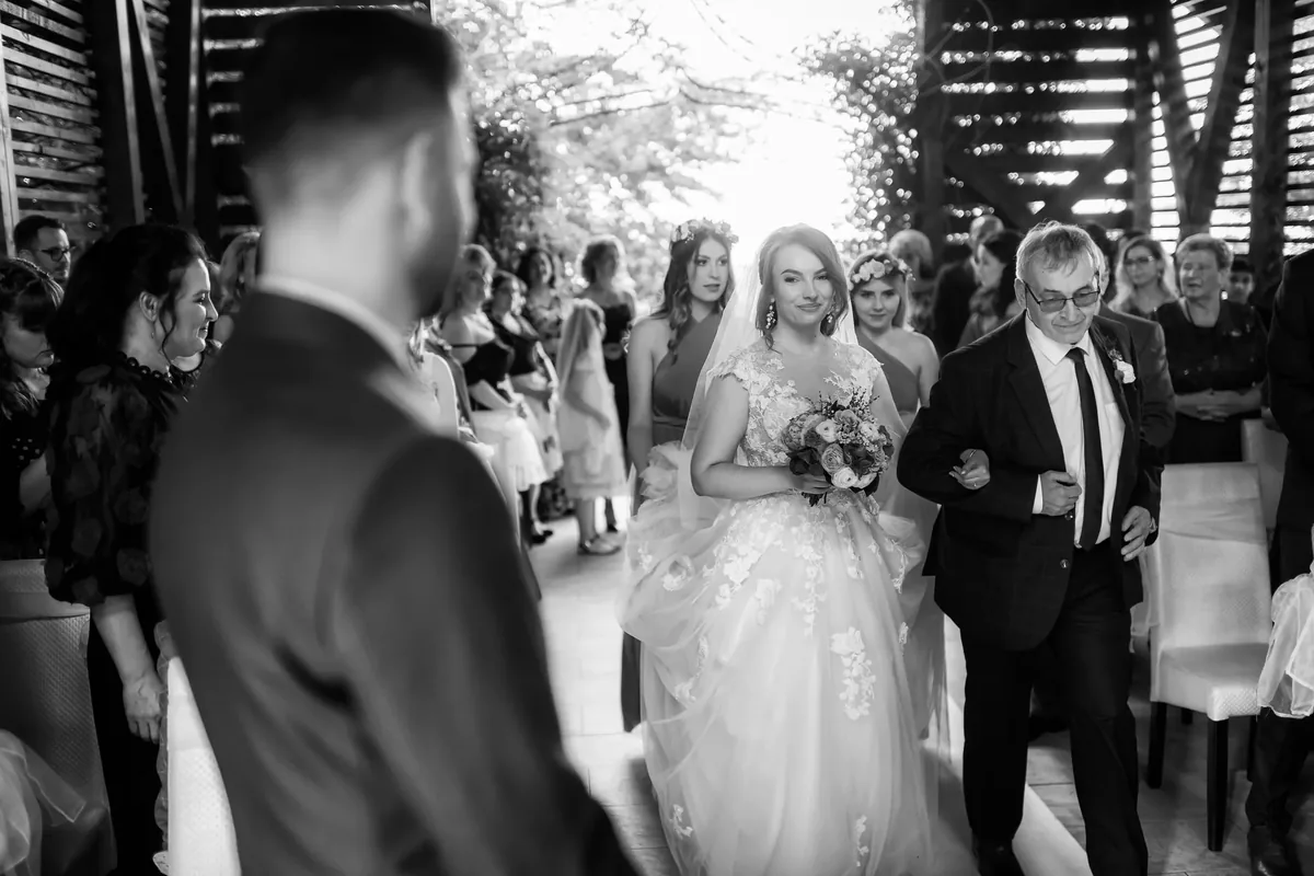 Mireasa intră pe culoarul capelei la brațul tatălui, invitații în picioare pe ambele laturi