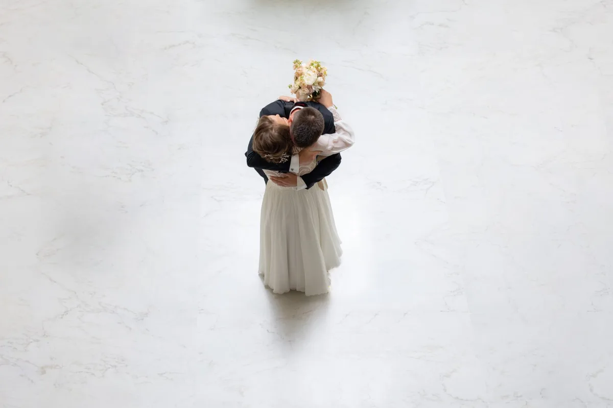 Îmbrățișare fotografiată de sus, de pe mezanin, pe marmura albă a lobby-ului
