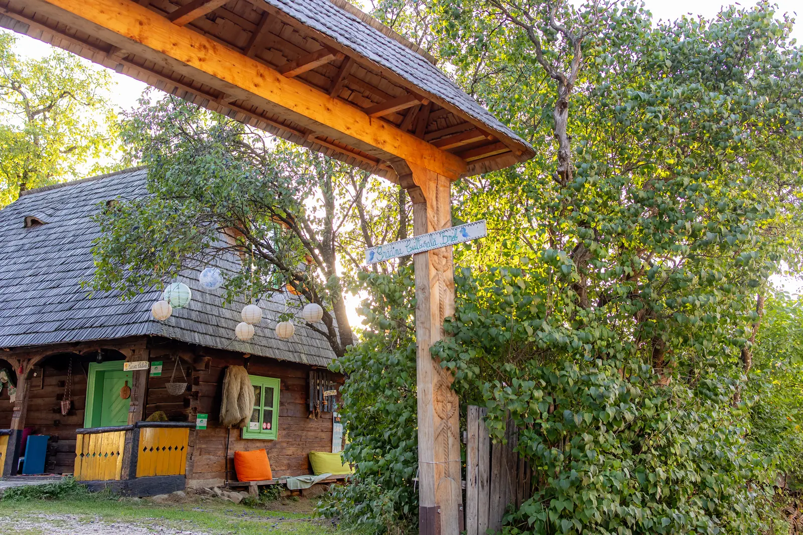 Casa de lemn cu poartă maramureșeană și lampioane aprinse, în seara dinaintea botezului