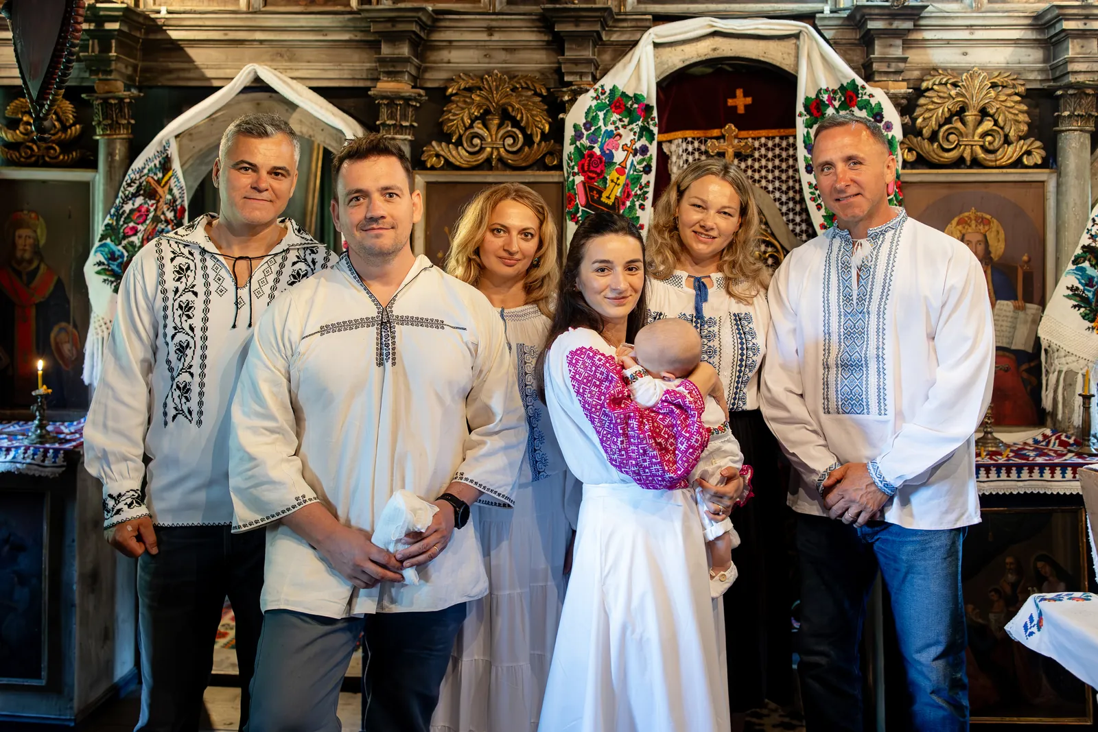 Fotografia de grup la iconostas, șapte adulți în ii cu bebelușul în mijloc