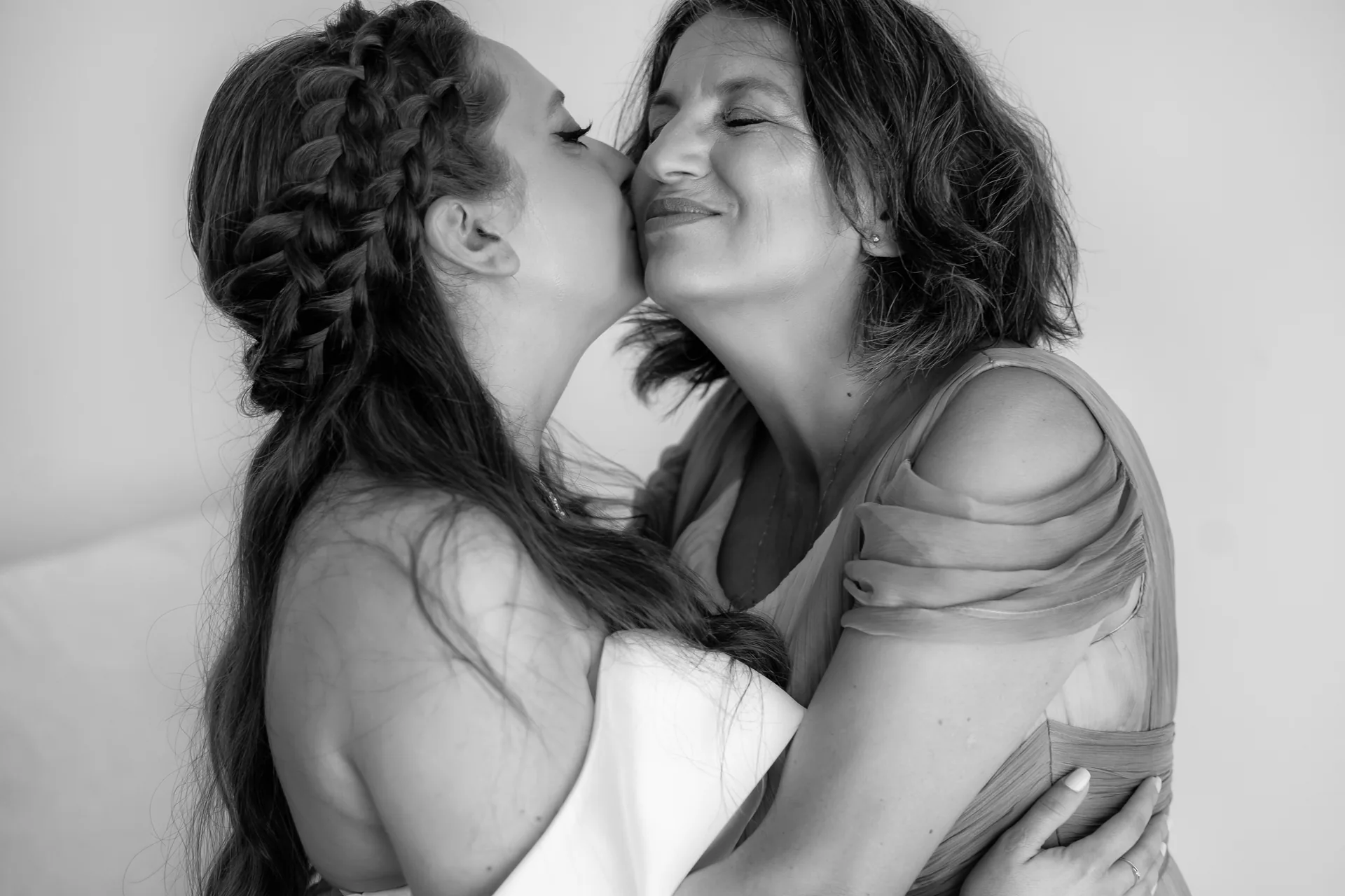 mireasa își sărută mama pe obraz, amândouă cu ochii închiși, alb-negru