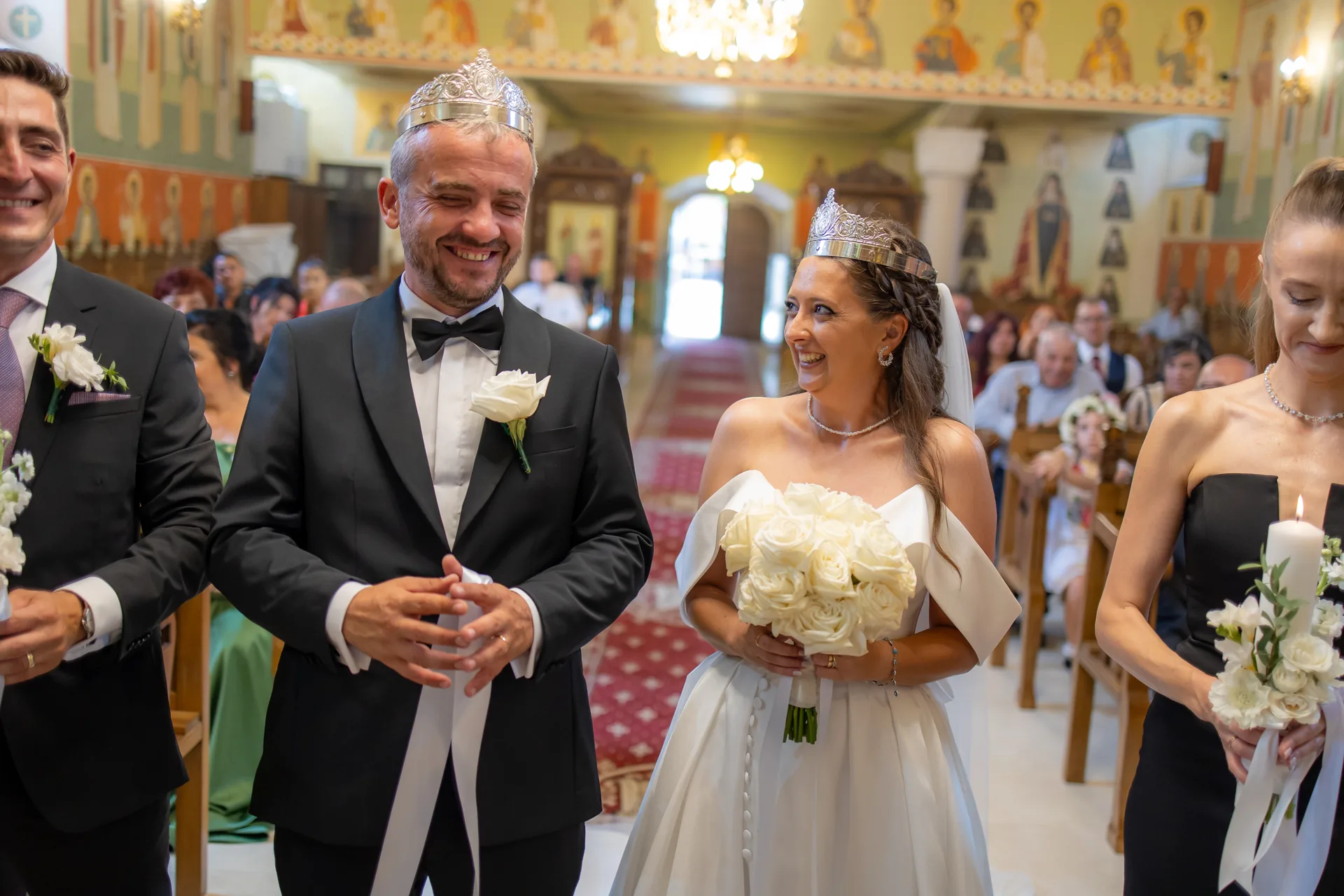 mirii cu cununiile pe cap, în fața altarului, zâmbind