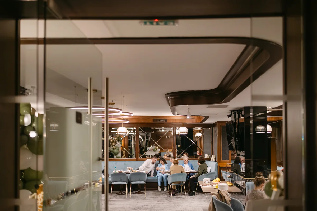 Salonul privat de la restaurantul Meridian, văzut prin uși de sticlă — interior elegant cu fotolii albastre, la un botez în Cluj-Napoca