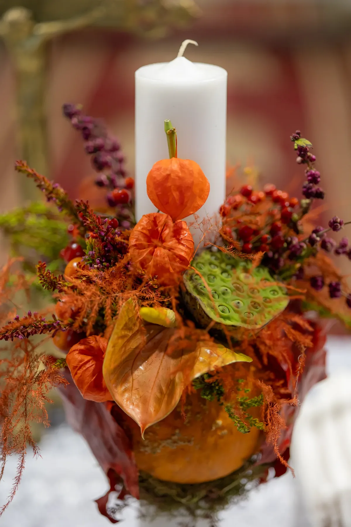 Lumânarea de botez decorată cu physalis portocaliu, păstăi de lotus și un dovleac mic