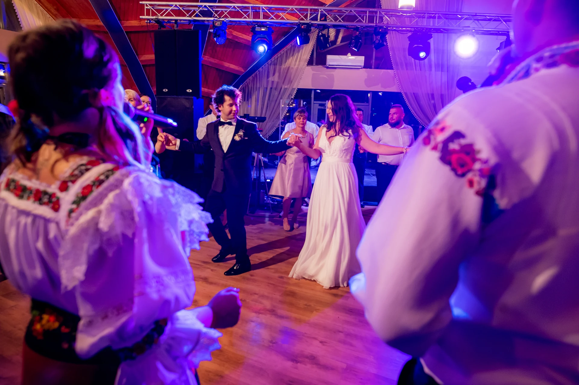 Mirii dansează cu invitații, încadrați de purtători de port maramureșean, la petrecerea de nuntă